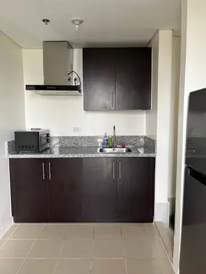 a kitchen with dark brown cabinets and a sink at Cozy Nook in the City in Manila