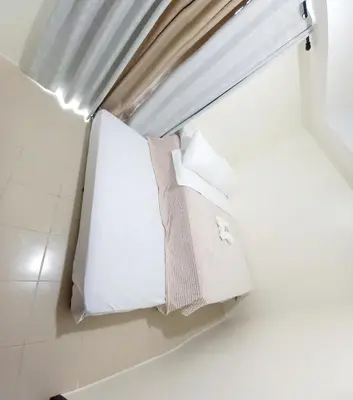 a room with white pillows and a window at Cozy Nook in the City in Manila