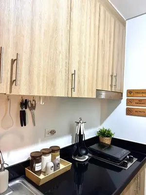 a kitchen with wooden cabinets and a black counter top at Philhaus Staycation in Manila