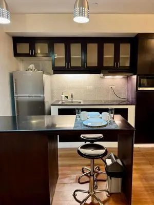 a kitchen with a counter with two bar stools at WestParc Cedar Cozy Apartment in the Heart of Alabang in Manila