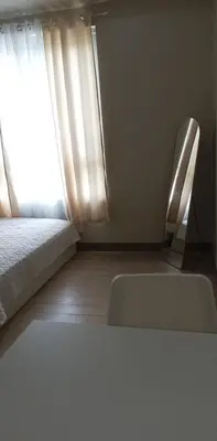 a room with a bed and a chair and a window at The Verdin Brand-New Unit with Pool, Gym, & High-Speed Wi-fi in General Trias