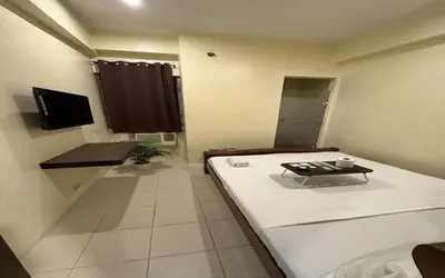 a room with a bed and a table in it at San Antonio's Place Suites in Manila