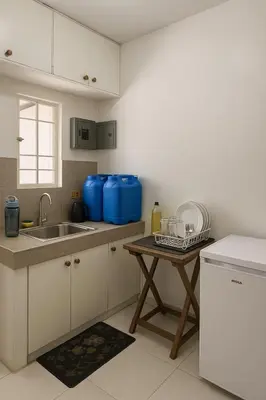 a kitchen with a sink and a table with blue tanks at Islana Stay Rm A for 1pax only in Imus