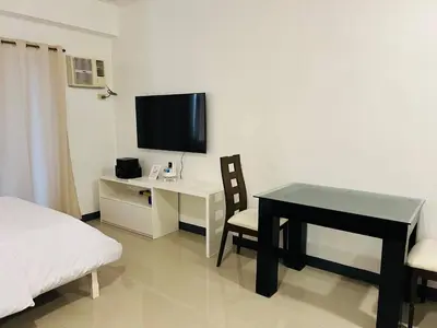 a bedroom with a desk and a bed and a television at Cozy Studio in Paraaque - Perfect for Transients and Long-Stayers Alike in Manila