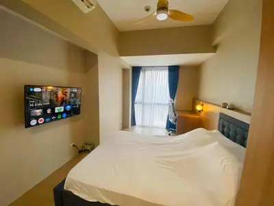 a bedroom with a white bed and a window at One Eastwood with mountain view in Manila