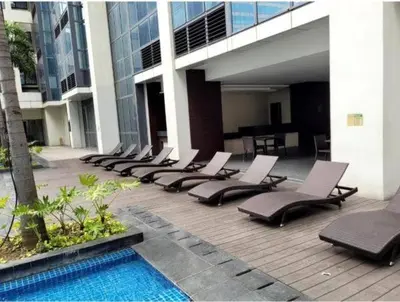 a row of lounge chairs sitting next to a pool at One Eastwood with mountain view in Manila