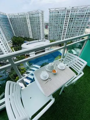 a table and chairs on a balcony with buildings at B&T Azure Staycation - Parañaque in Manila