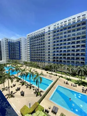 a large apartment building with two pools and palm trees at The Tenth Balcony in Manila