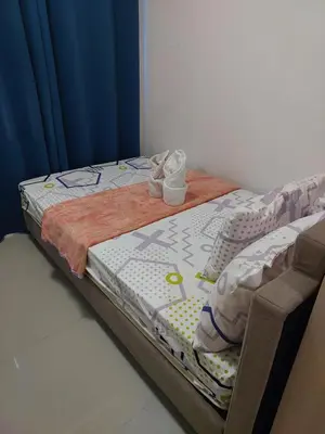 a small bed in a room with a blue curtain at AilynSea residence staycation in Manila