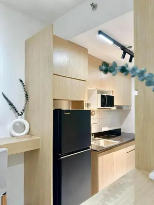 a kitchen with a black refrigerator and wooden cabinets at Mujihomes - 1BR SMDC Fame Residences Mandaluyong in Manila
