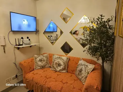 a living room with an orange couch and a tv at Staycation near MOA, SMX Convention, DFA, NAIA in Manila