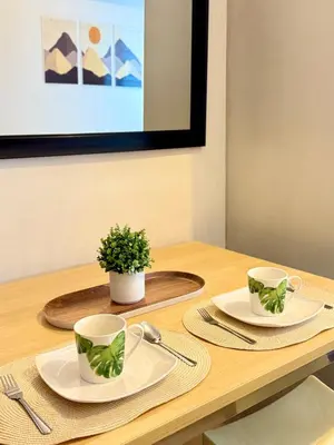 a wooden table with two plates and two cups on it at SMDC Light Residences - Studio Condo Unit in Manila