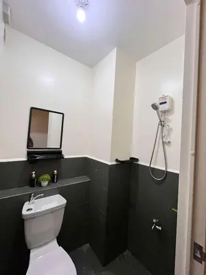 a bathroom with a toilet and a shower with a mirror at Mars Condo Unit in Manila