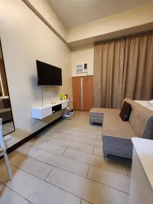 a living room with a couch and a flat screen tv at Two Palm Tree Villas Across NAIA Terminal 3 in Manila