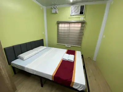 a bedroom with a bed in a room with a window at Sunrise Dormitel in Manila