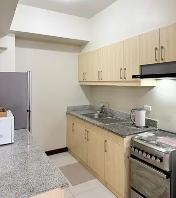 a kitchen with wooden cabinets and a stainless steel refrigerator at Corner 37 at Lumiere Residences in Manila