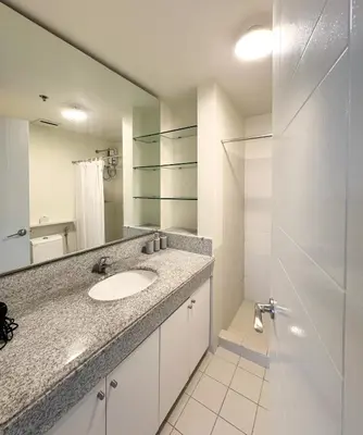 a bathroom with a sink and a mirror and a shower at Corner 37 at Lumiere Residences in Manila