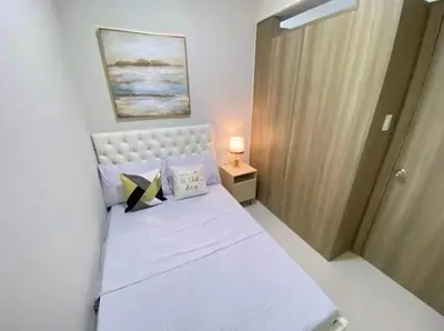a small bedroom with a white bed and a door at SMDC Coast Residence in Manila