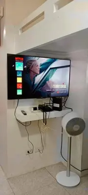 a flat screen tv hanging on a wall with a stool at Close by landmarks and airport in Manila