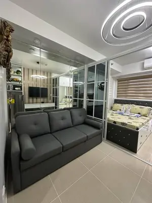 a living room with a couch and a bed at Bellas Place Shell Residences MOA in Manila