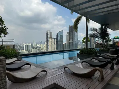 a swimming pool with chairs and a view of a city at Apartment in Salcedo village, Makati City in Manila