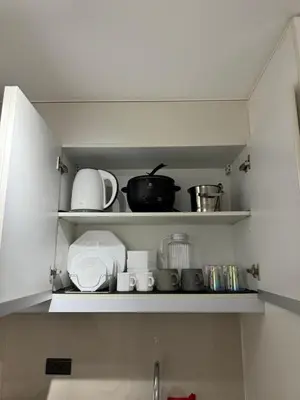 a kitchen shelf filled with dishes and pots and pans at Apartment in Salcedo village, Makati City in Manila