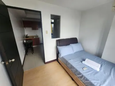 a small bedroom with a bed and a small kitchen at Bayport Luxhome in Manila