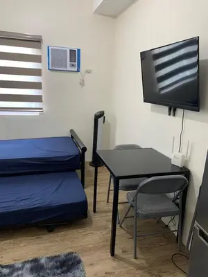 a room with two beds and a table and a tv at M&L Condotel in Santo Domingo