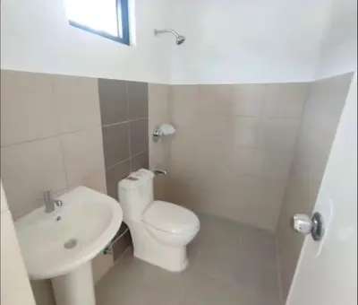 a white bathroom with a toilet and a sink at Transient Room in Dasmariñas