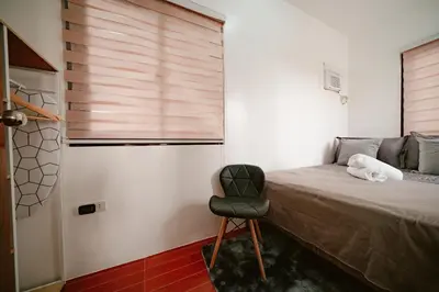 a bedroom with a bed with a chair and a window at Picturesque 3BR home near Thunderbird, Overlooking in Binangonan