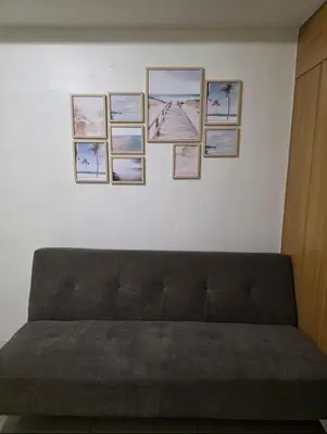 a couch against a white wall with pictures on it at Staycation with Netflix in Shell Residences in Manila