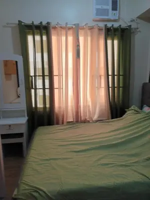a bedroom with a bed with green sheets and a window at Nature Green Room Paseo Verde at Calle Real in Manila