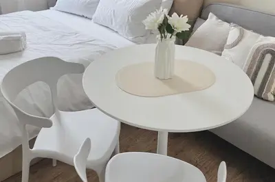 a white table with a vase of flowers on it next to a bed at Cozy Elegance Staycation in Silang