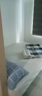 a white bed with a blue pillow and towels at Tower C sea residence manolita in Manila