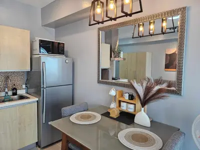 a kitchen with a table and a refrigerator at Ashley's Chamber at Soho Central across Shangrila Mall in Manila