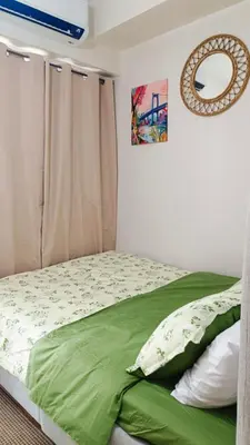 a bedroom with a bed with green sheets and a mirror at Cozy Space at Red Makati City in Manila
