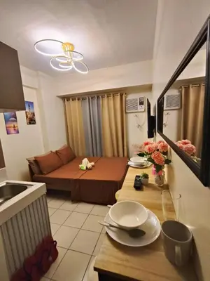 a small living room with a bed and a table at g and A condotels in Manila