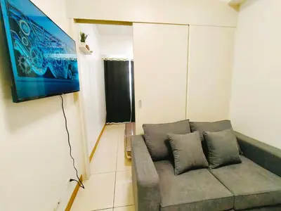 a living room with a couch and a flat screen tv at Cozy 2BR Stay Near SM Southmall in Manila