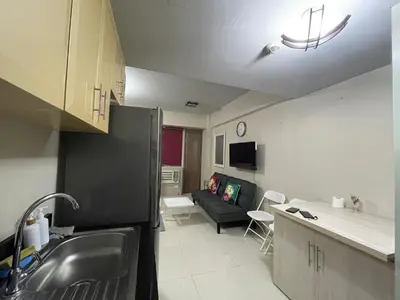a kitchen and living room with a black refrigerator at Cozy condy at One palm villa across NAIA T3 in Manila