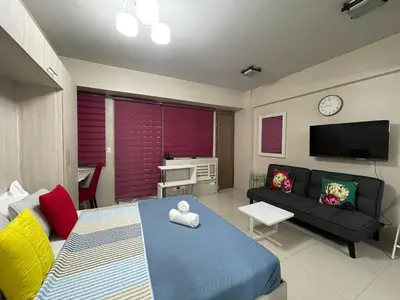 a living room with a bed and a couch at Cozy condy at One palm villa across NAIA T3 in Manila