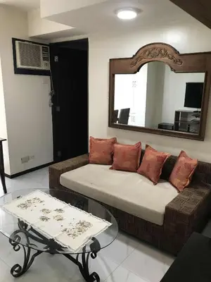 a living room with a couch and a mirror at A venue Residences 2013 in Manila
