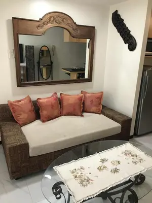 a living room with a couch and a mirror at A venue Residences 2013 in Manila