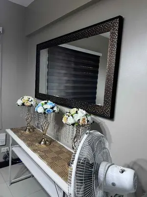 a mirror above a table with flowers and a fan at The Haru at Arista in Manila