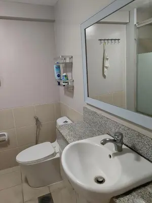 a bathroom with a sink and a toilet and a mirror at Resort inspired Alea residences in Manila