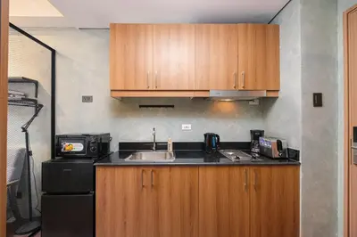 a kitchen with wooden cabinets and a sink and a refrigerator at SMDC Lush The Forge in Manila