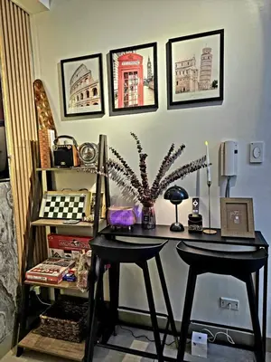 a desk with two stools in a room with pictures on the wall at Irene's luscious place in Manila