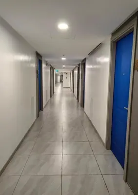 an empty hallway in an office building with a blue door at Modern Minimalist City Views in Prime Location in Manila