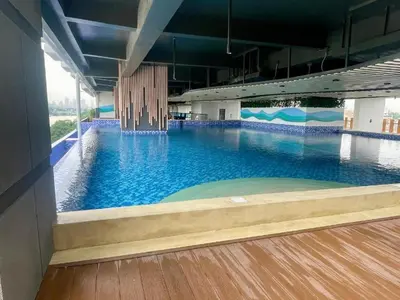 a large swimming pool with blue water in a building at Modern Minimalist City Views in Prime Location in Manila