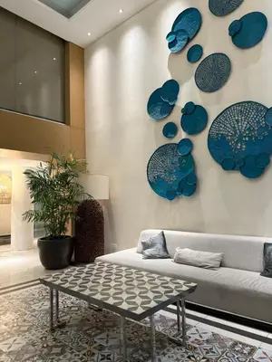a living room with a couch and blue plates on the wall at Nook Out at Azure Urban Residences in Manila