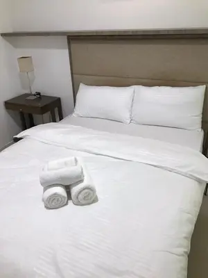 a white bed with two rolled towels on it at Antel Spa Residences 10B in Manila